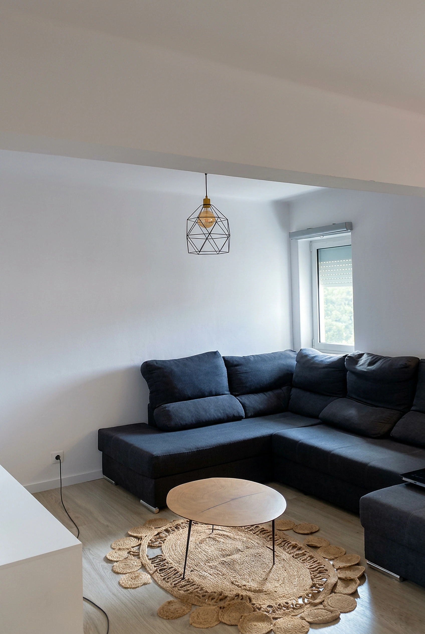 Sala de estar com sofá em L e tapete redondo de juta