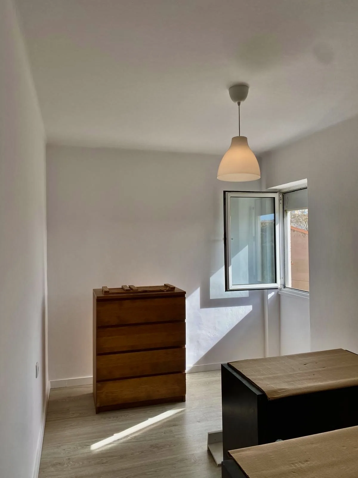 Quarto remodelado com paredes brancas e cómoda em madeira